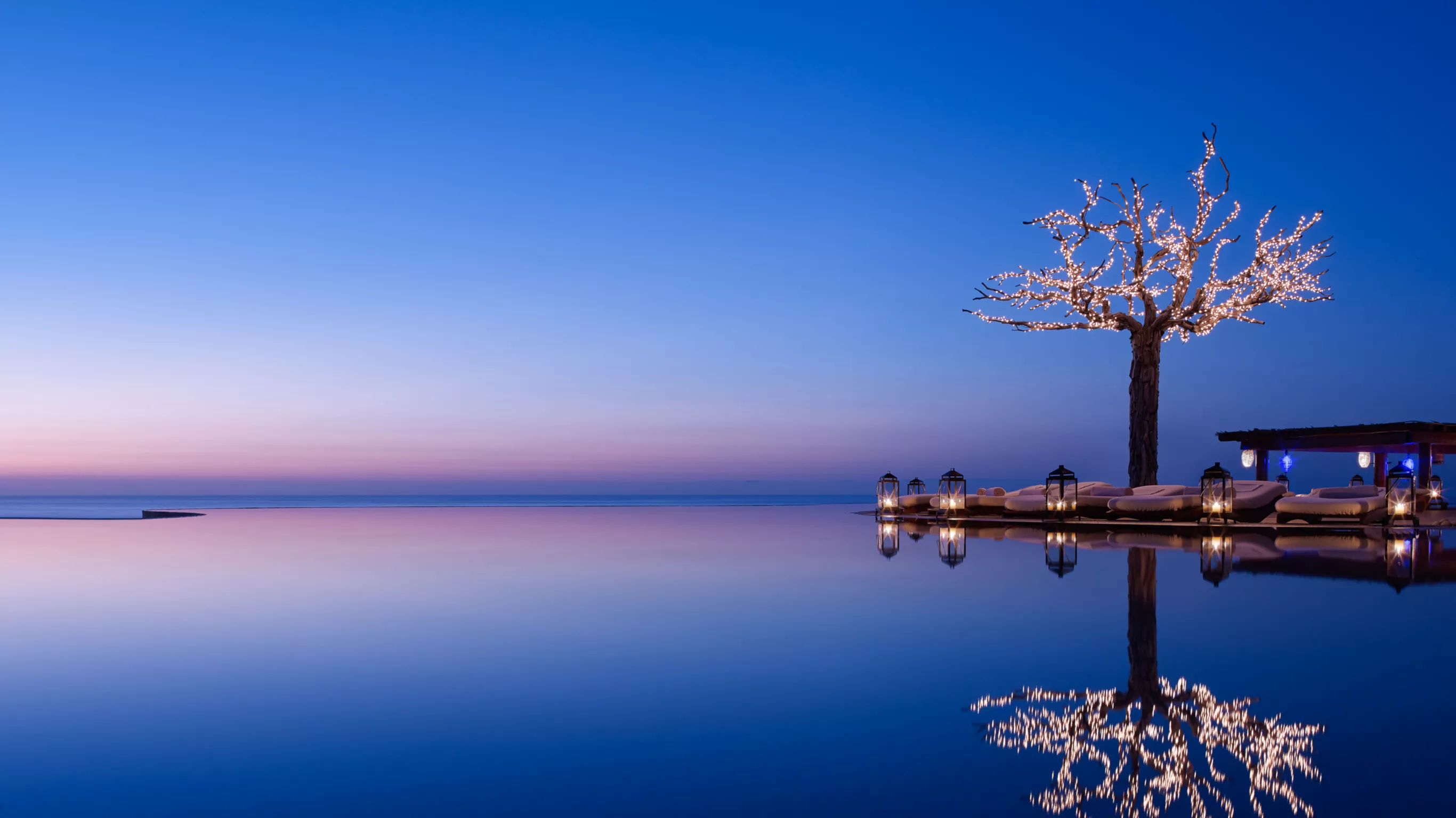 Las Ventanas al Paraíso — iconic infinity pool at twilight with illuminated tree reflected in the still water