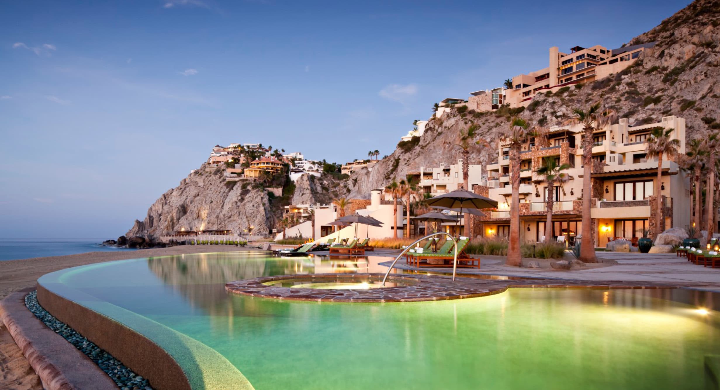 Waldorf Astoria Los Cabos Pedregal — infinity pool at dusk carved into the cliffs above the Pacific Ocean