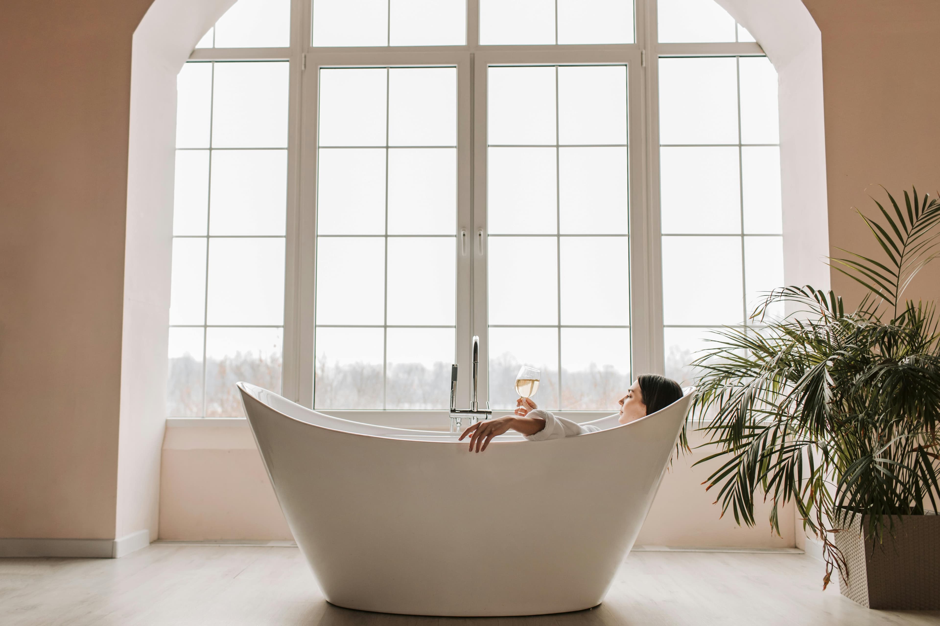 Luxury freestanding soaking tub by arched floor-to-ceiling windows in a high-end Cabo villa spa suite