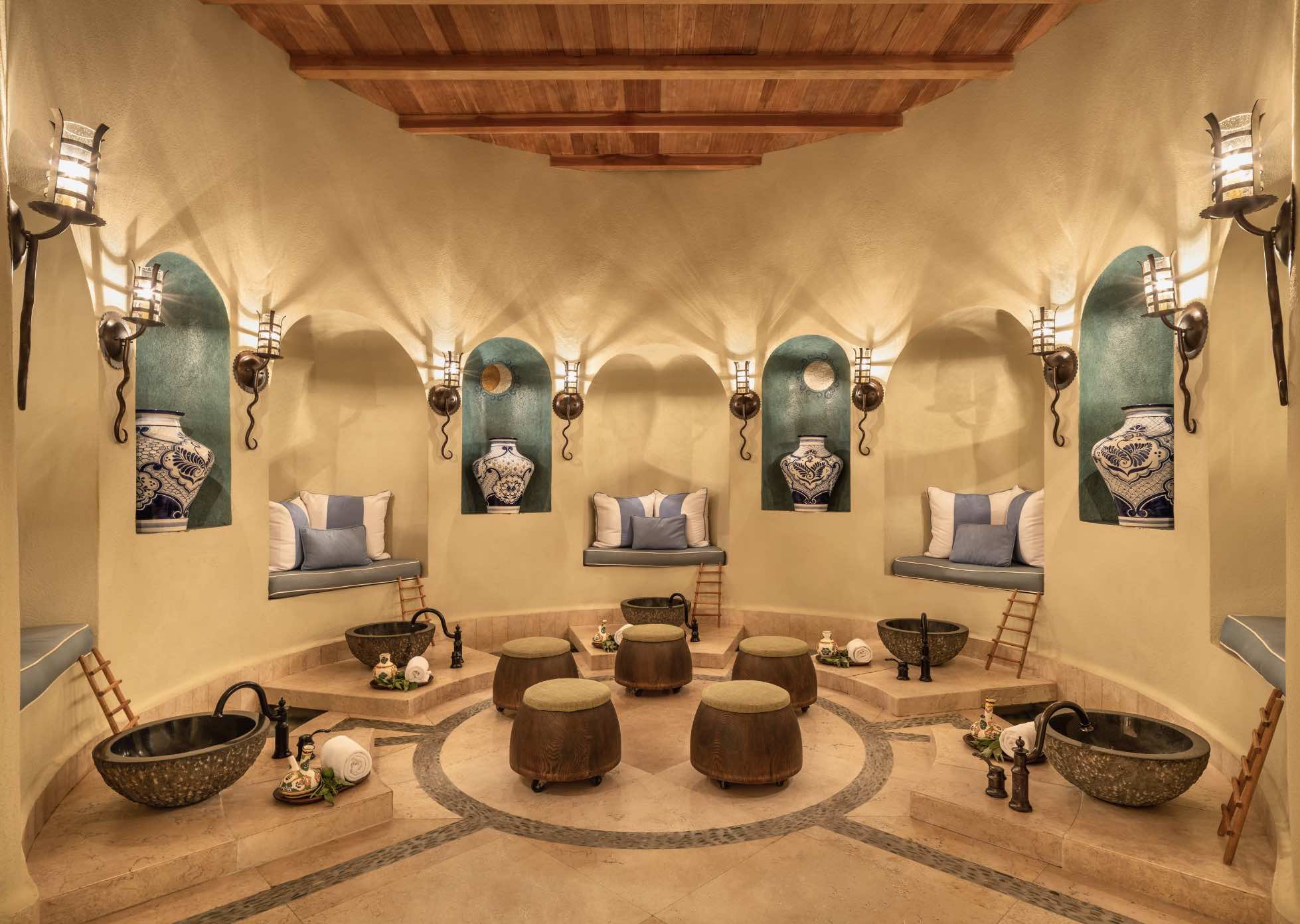 Ornate circular spa treatment room with arched niches, talavera pottery, iron sconces, and stone basins at a world-class Los Cabos resort